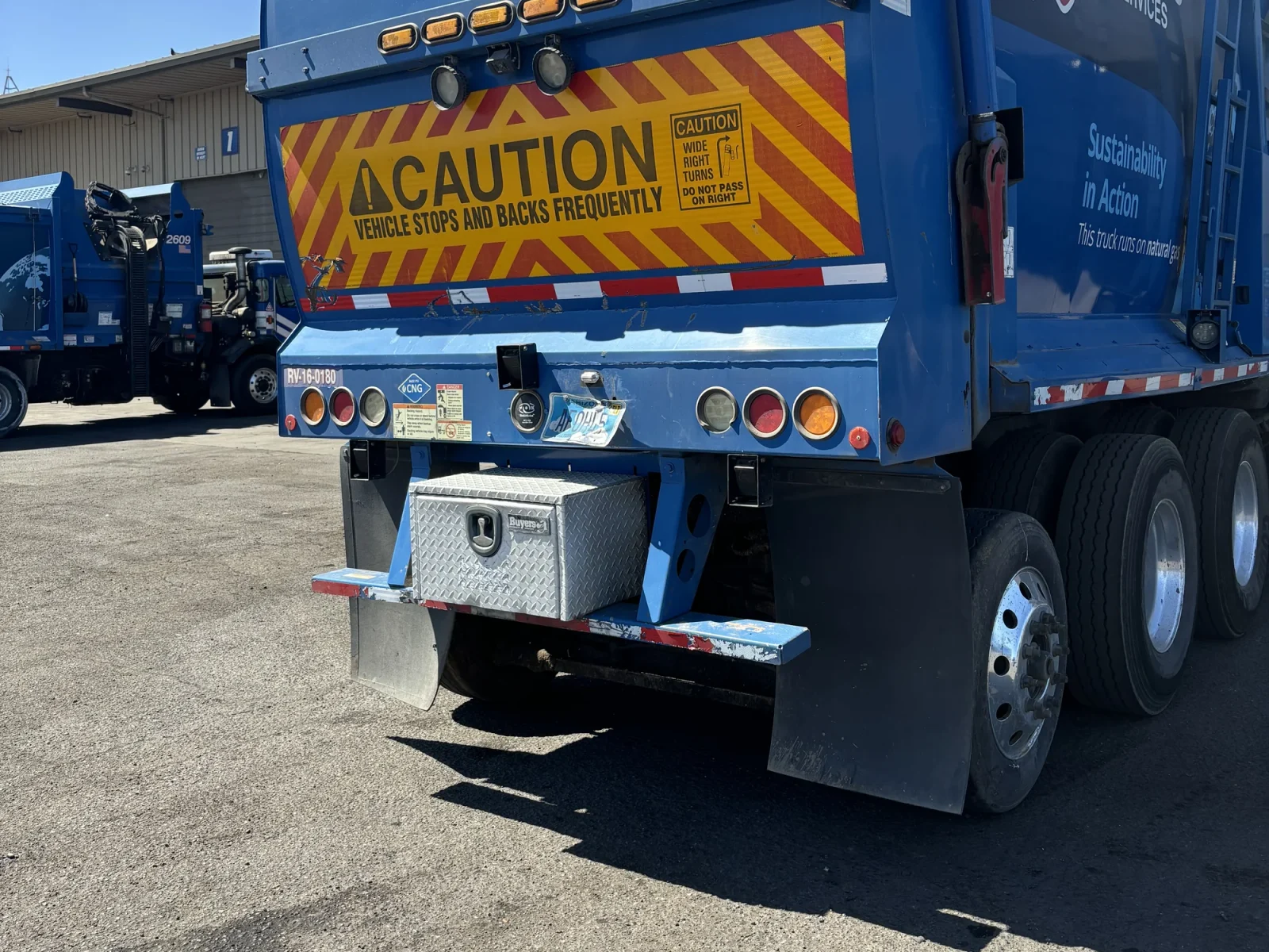 Rear quarter of a Republic Services front-load truck parked in a yard
